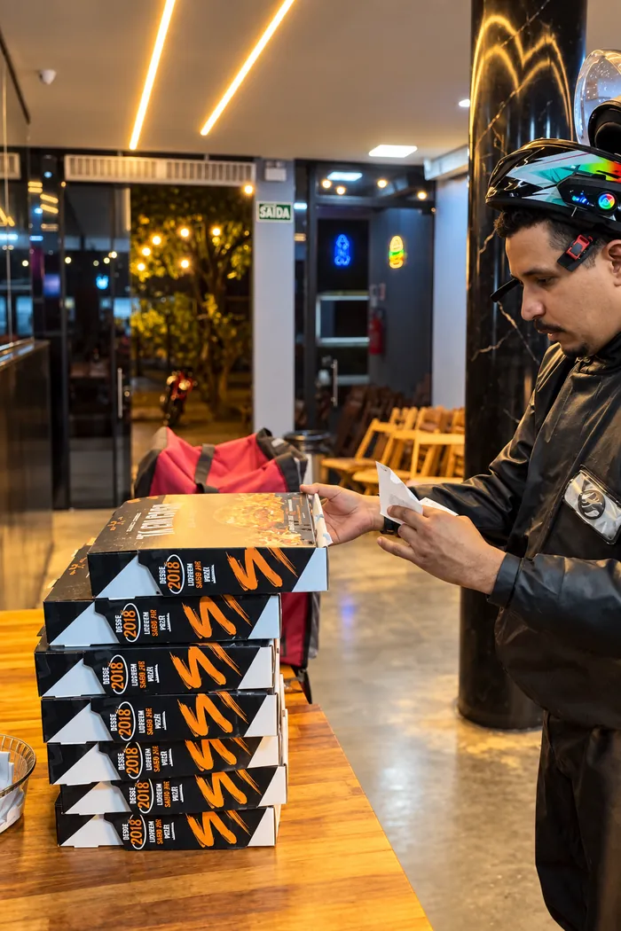 Entregador retirando caixas de combos da Tá Em Casa para delivery