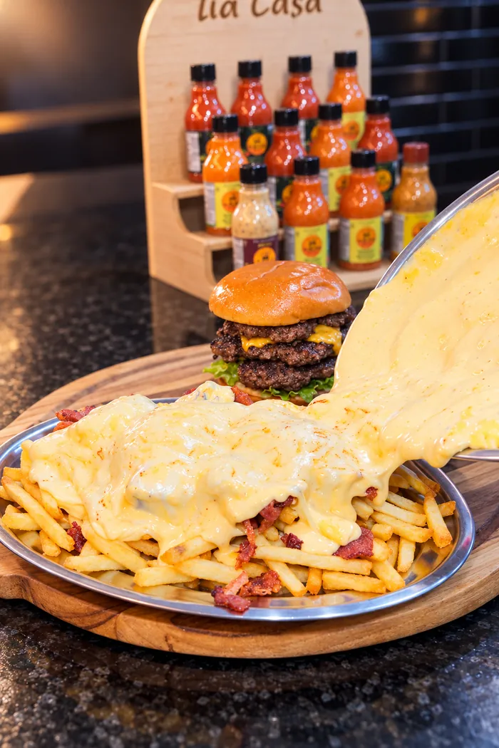 Hambúrguer com fondue de cheddar derretido sobre a batata