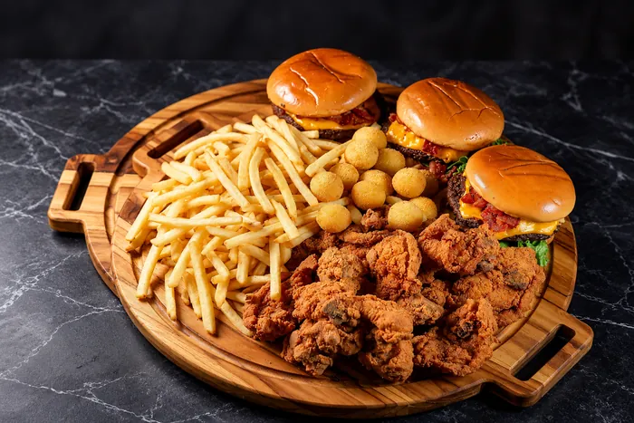 Tábua com lanches, frango frito, bolinhas de queijo e batata